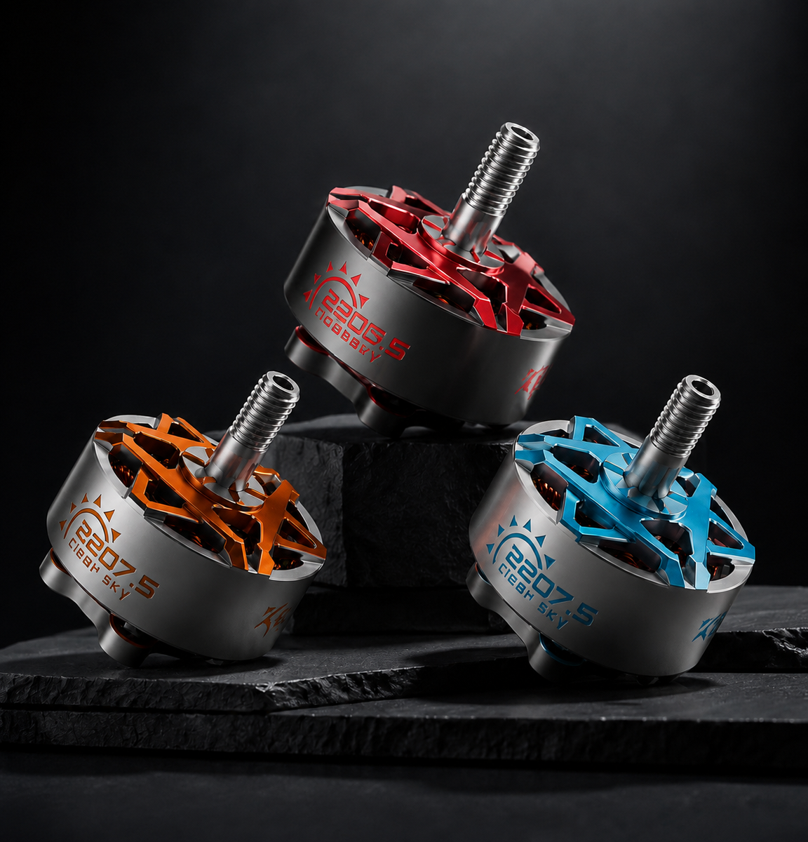 Three brushed motor brushless drone components with silver metal bodies, colorful anodized star-shaped splashes in red, orange, and blue, and silver threaded shafts, displayed on a dark slate surface against a black background.