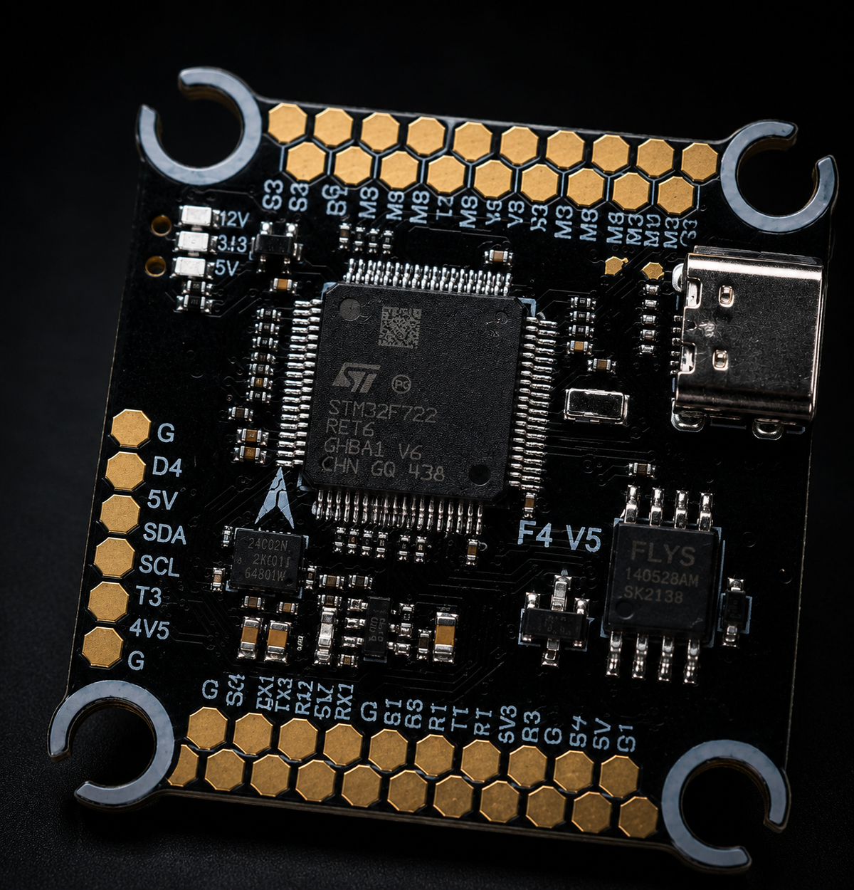 A close-up of a black electronic circuit board with gold-plated connectors and components, featuring a central STMicroelectronics STM32F722 microcontroller and a USB-C port, set against a dark background.